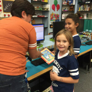 Two students receive help checking out books from the Summitt Library